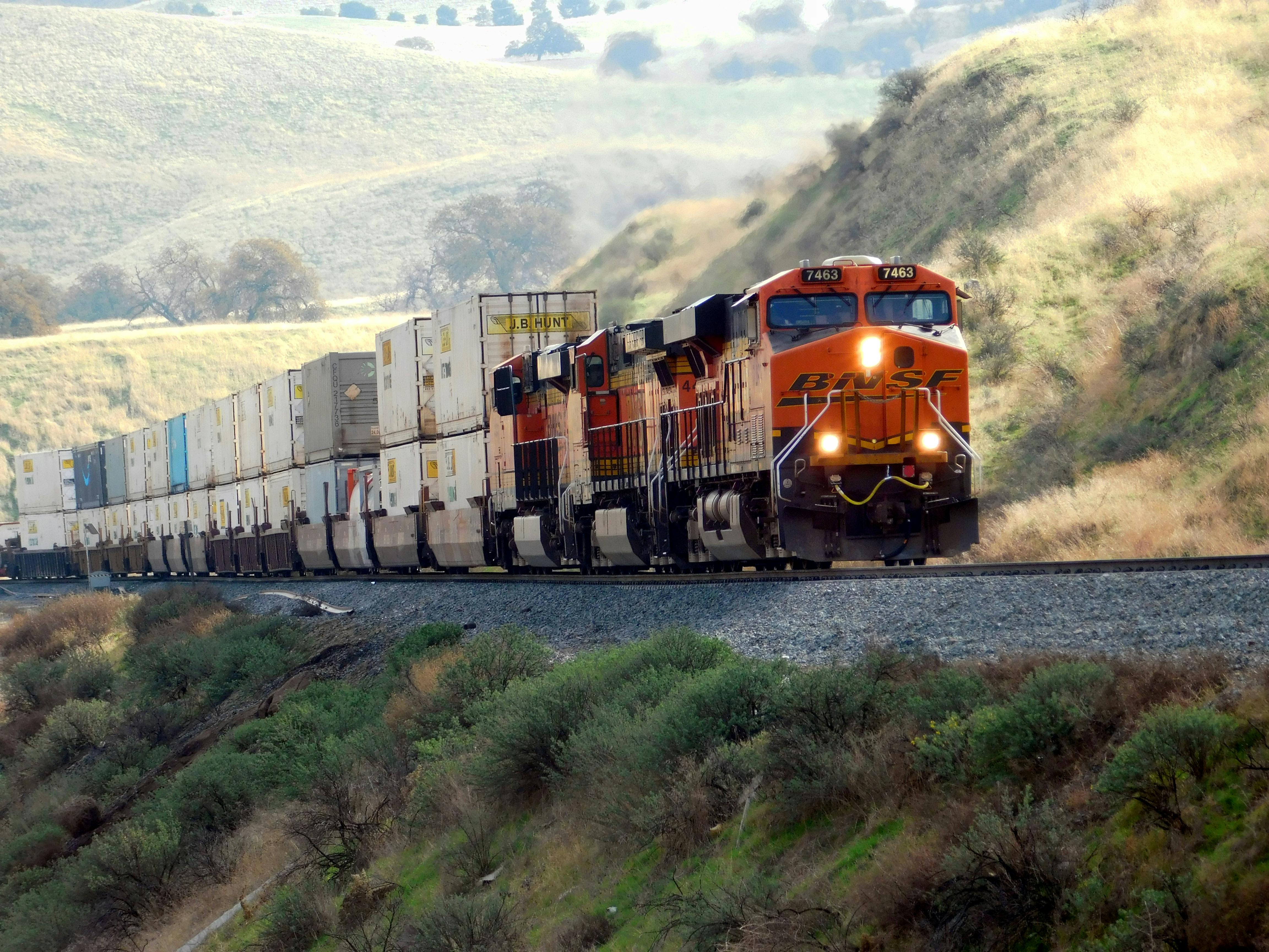 Freight train hauling stacked containers through a hillside route